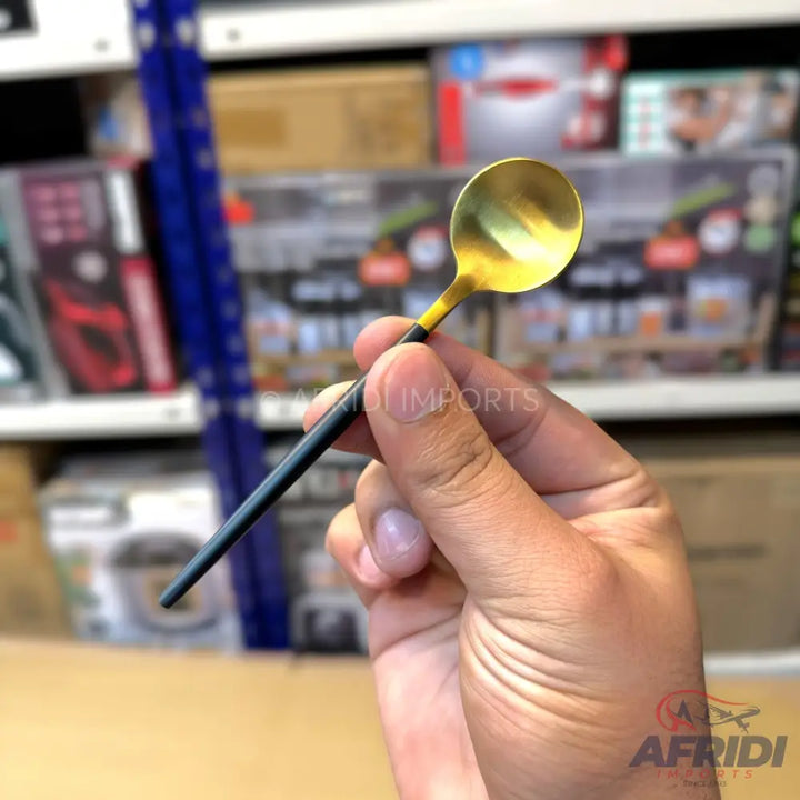 A small golden spoon with a black handle.