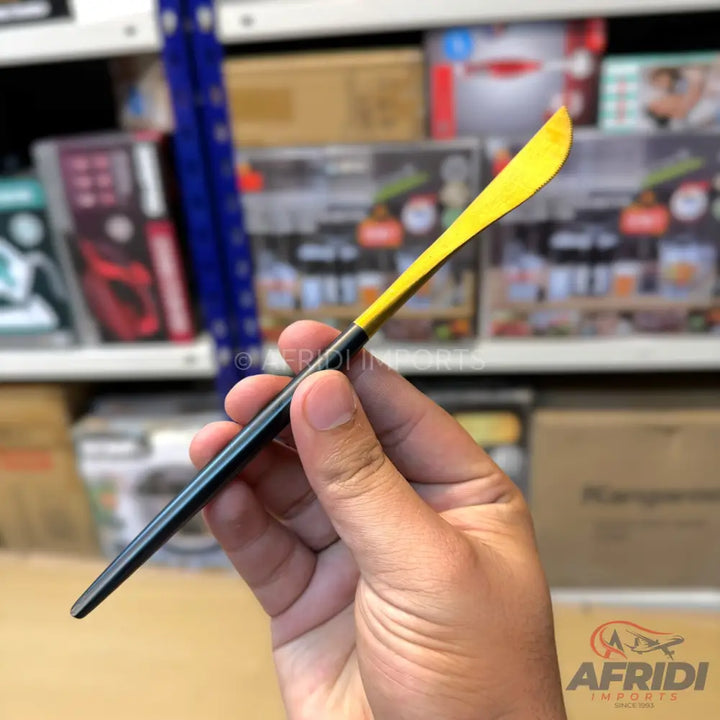 A hand holding a small yellow and black butter knife.