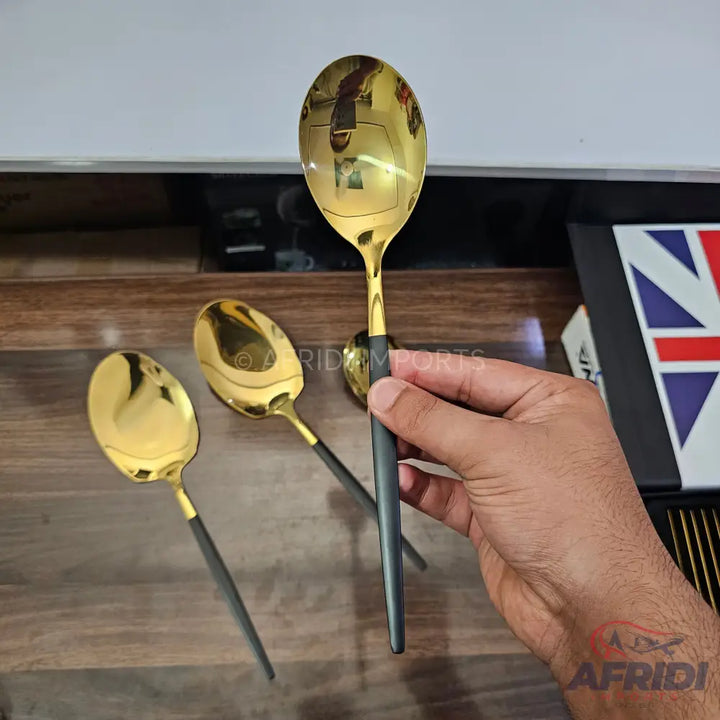 A gold-colored spoon with a black handle.