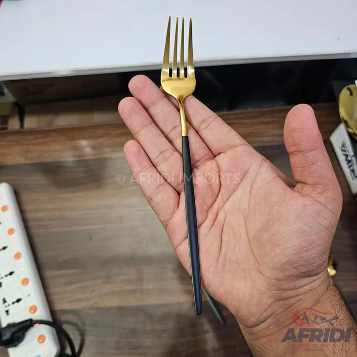 A gold-colored fork with a black handle.