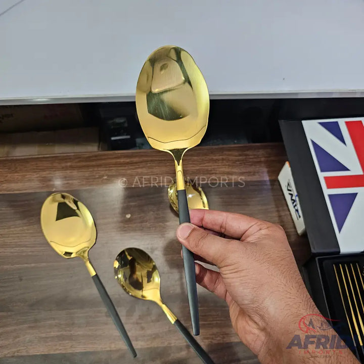 Gold-colored spoon with a black handle.