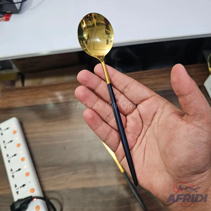 A sleek, two-toned spoon with a golden bowl and a black handle.