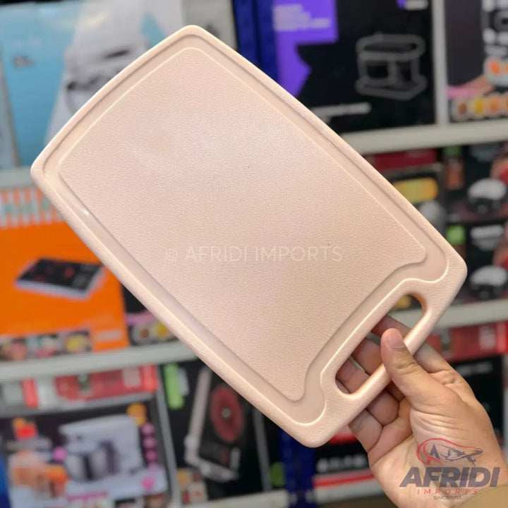 Light pink plastic rectangular cutting board with a handle.