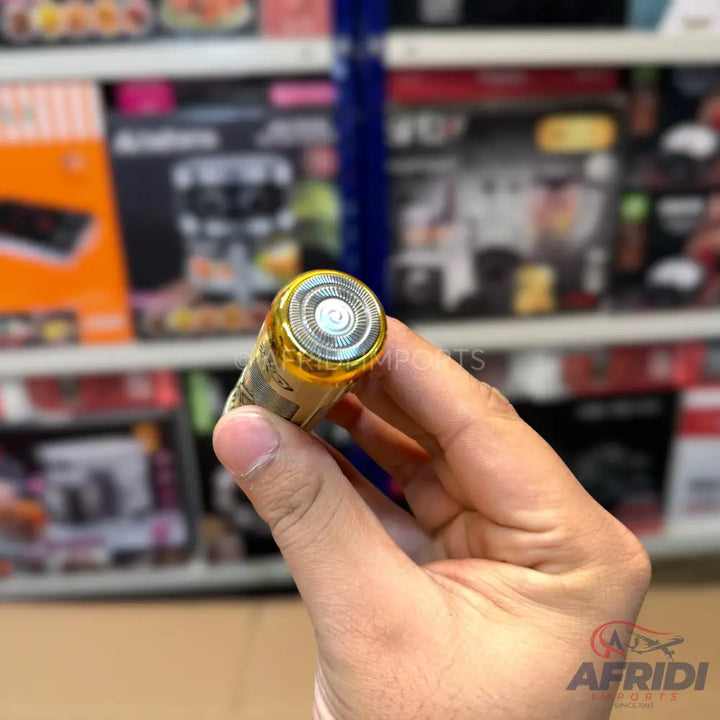A compact, portable electric shaver with a gold-colored rotating head.