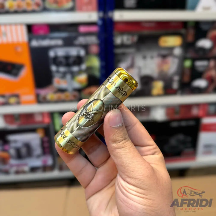 Gold-colored metal cylindrical perfume atomizer with intricate engravings.