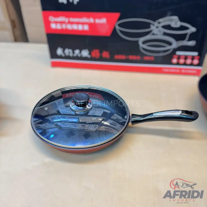Red frying pan with a clear glass lid and black handle.