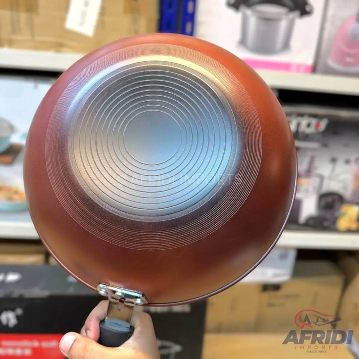 The bottom of a reddish-brown non-stick frying pan with concentric circular grooves.