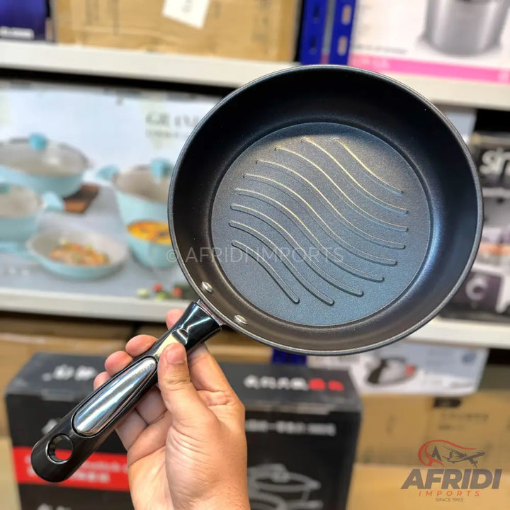 Black non-stick frying pan with a ribbed bottom and a black and silver handle.