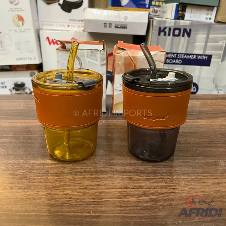 Two insulated glass tumblers with straws and leather sleeves.