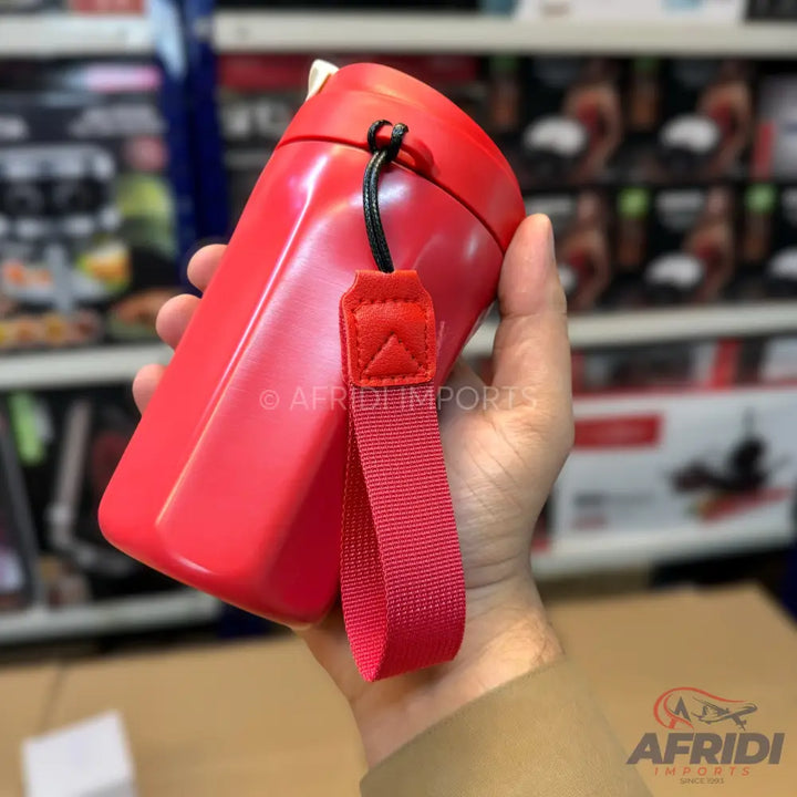 Red plastic water bottle with a black string and red fabric carrying strap.