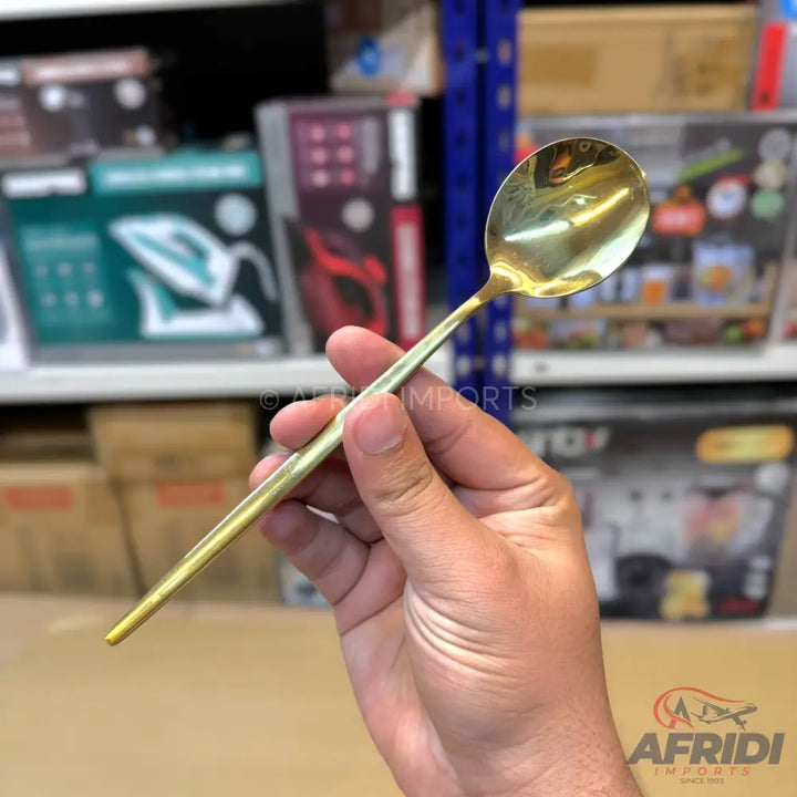 A gold-colored metal spoon with a slender handle.