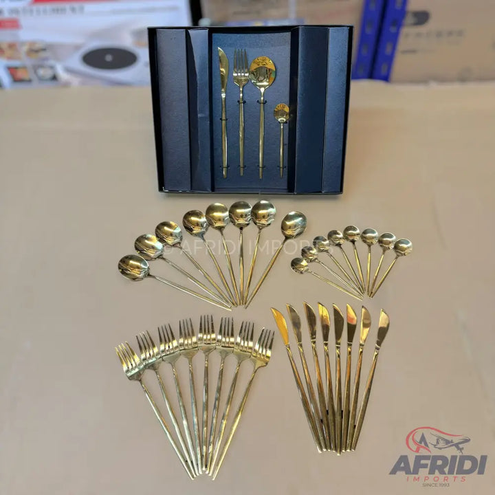 A comprehensive gold-colored cutlery set, including various spoons, forks, knives, and a boxed serving set.