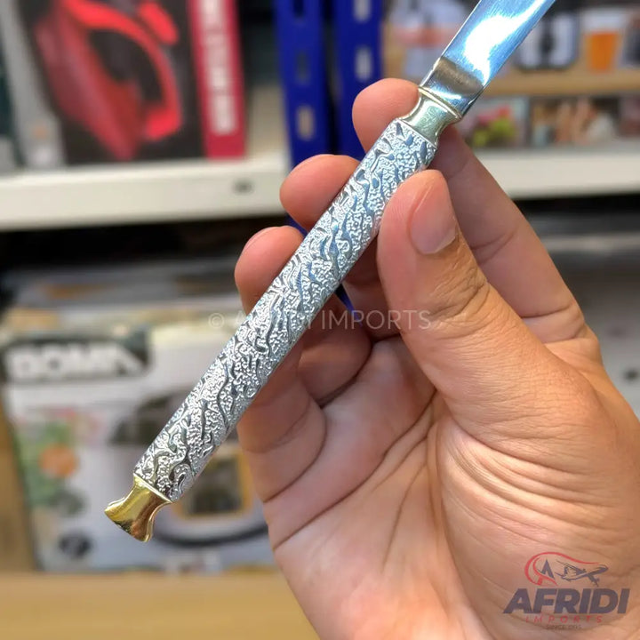Silver-patterned butter knife with a gold-colored end.