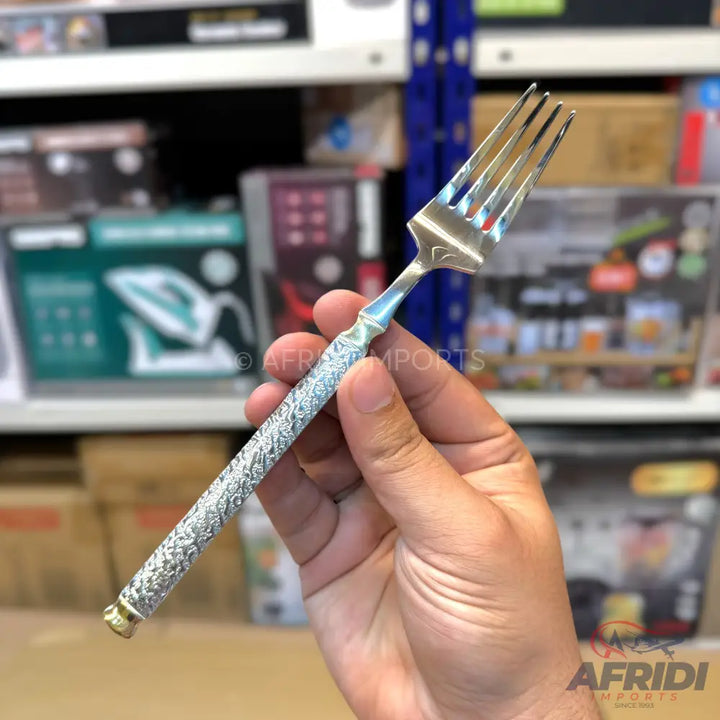 Silver-colored fork with an ornate, textured handle and four prongs.