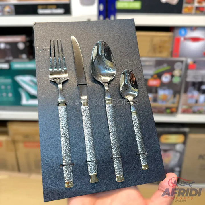 A four-piece set of silver-colored cutlery with textured handles and brass accents.