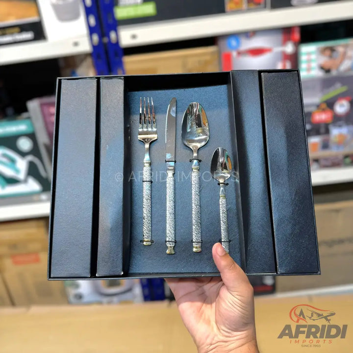 A four-piece silver cutlery set with textured handles, presented in a black gift box.