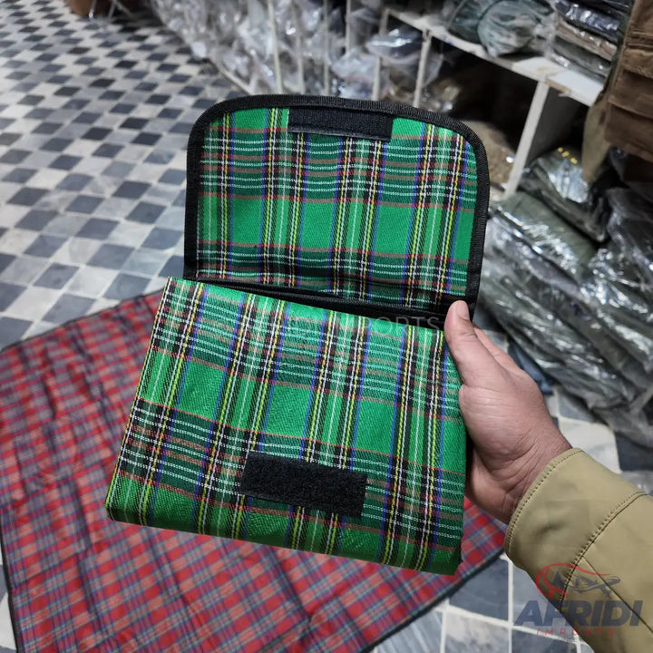 A green plaid patterned soft case with a black velcro closure.