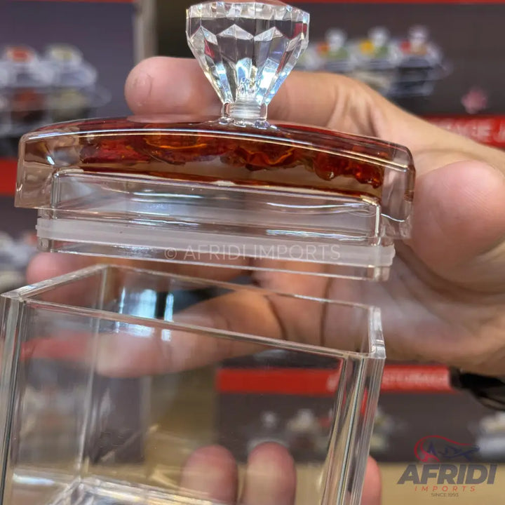 A clear acrylic storage container with a faceted diamond-shaped lid handle.