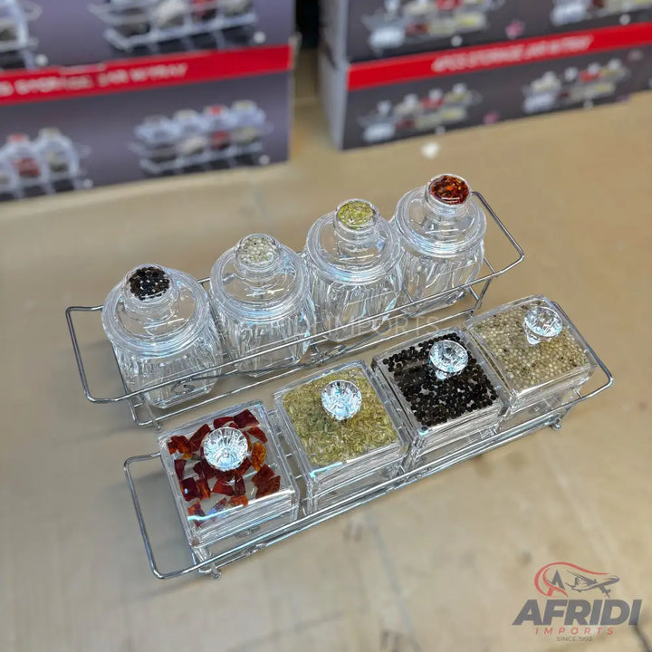 Two sets of clear glass spice jars with decorative lids on metal racks.