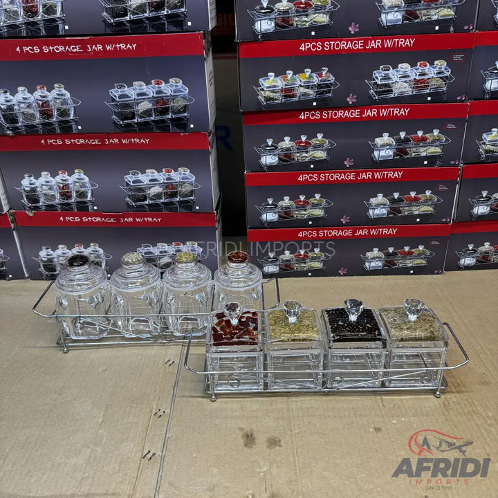 A set of four clear glass storage jars with diamond-shaped lids, presented on a metal tray, designed for spices or other dry goods.