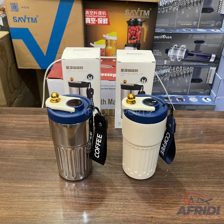 Two insulated coffee tumblers, one silver and one off-white, with dark blue lids and ’COFFEE’ straps.
