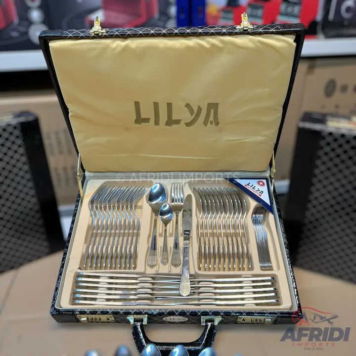 A comprehensive set of silver-colored cutlery, including spoons, forks, and knives, neatly arranged in a black, patterned presentation case with a cream-colored interior.