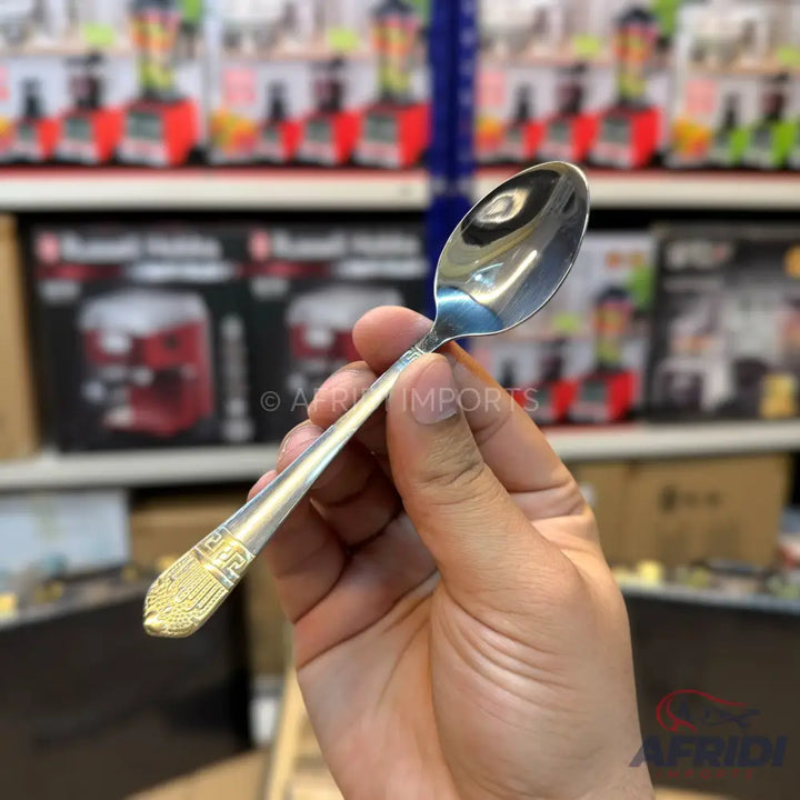 Shiny silver spoon with a gold patterned handle.