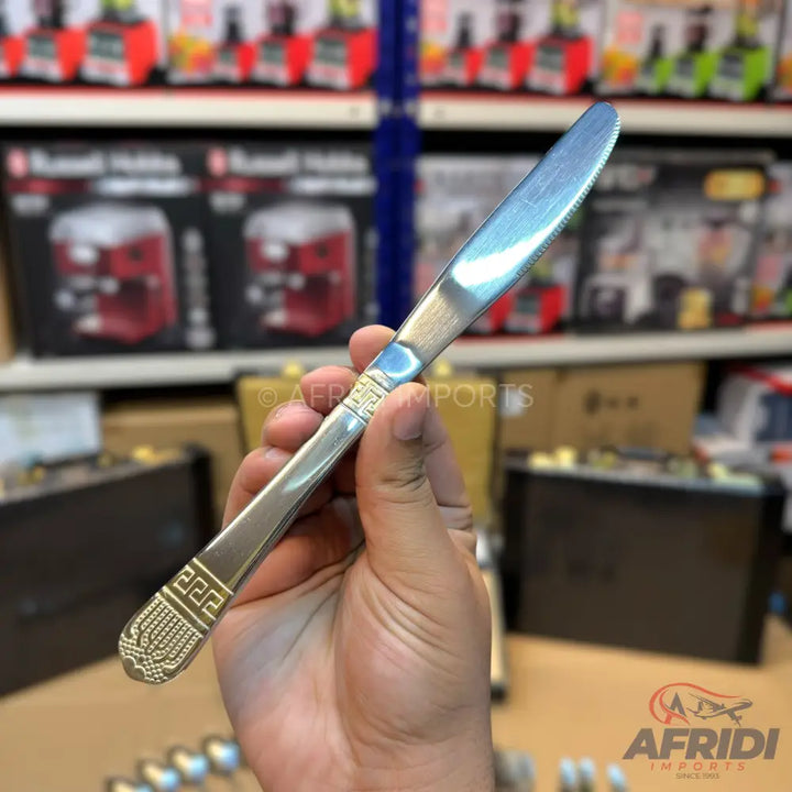 A stainless steel dinner knife with an ornate, embossed handle.