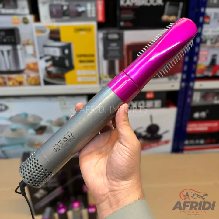 Pink and gray hot air styler with a brush attachment.