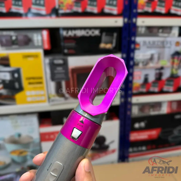 A handheld, magenta and silver hair styling tool with an open, oval-shaped nozzle.