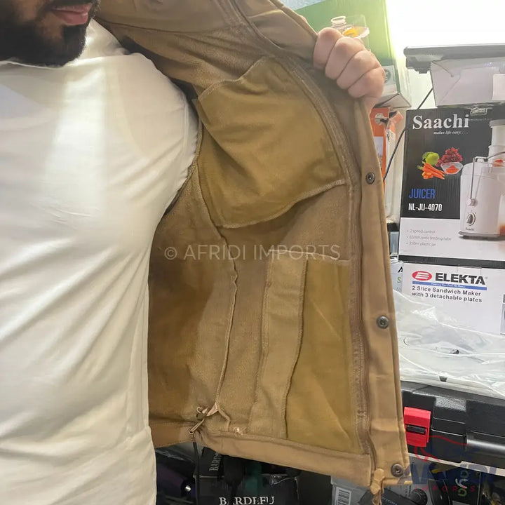 A person wearing a tan jacket with multiple interior pockets.