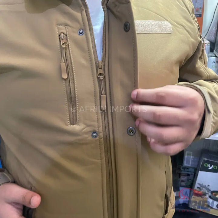 Tan tactical jacket with multiple zippers and snap buttons.