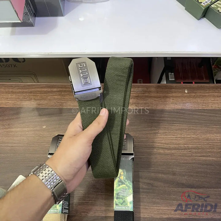 An olive green canvas belt with a metallic buckle.