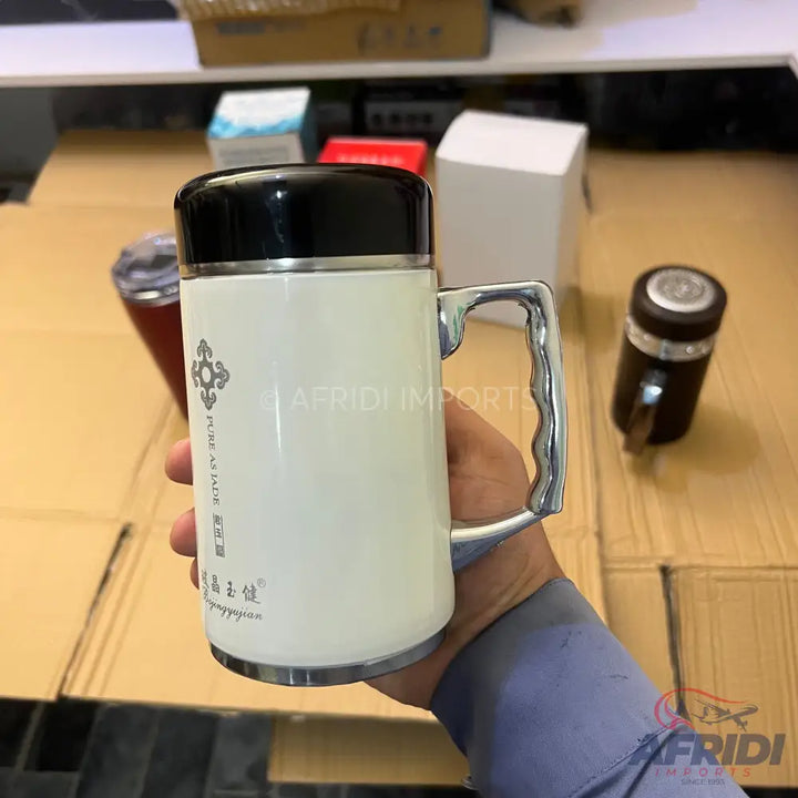 White travel mug with a black lid and a silver handle.