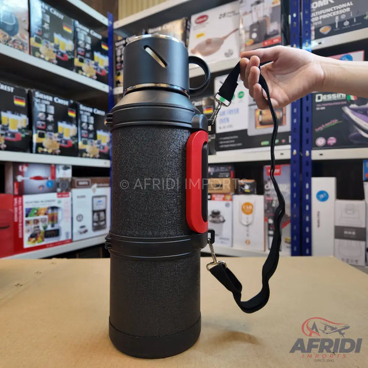Black insulated beverage dispenser with a red handle and carrying strap.