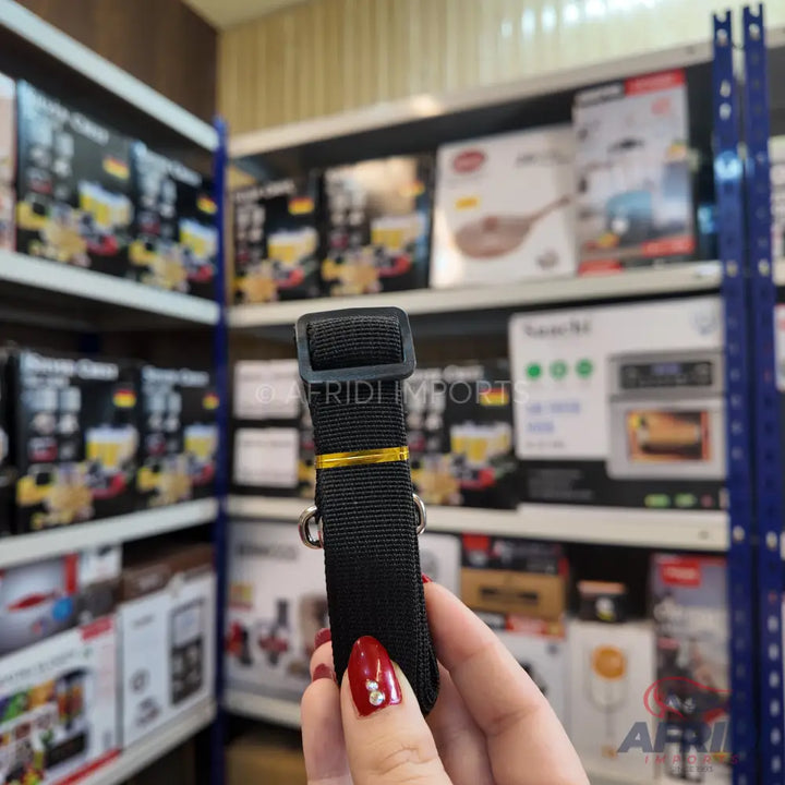 Black nylon strap with a plastic buckle and metal rings, held by a hand.