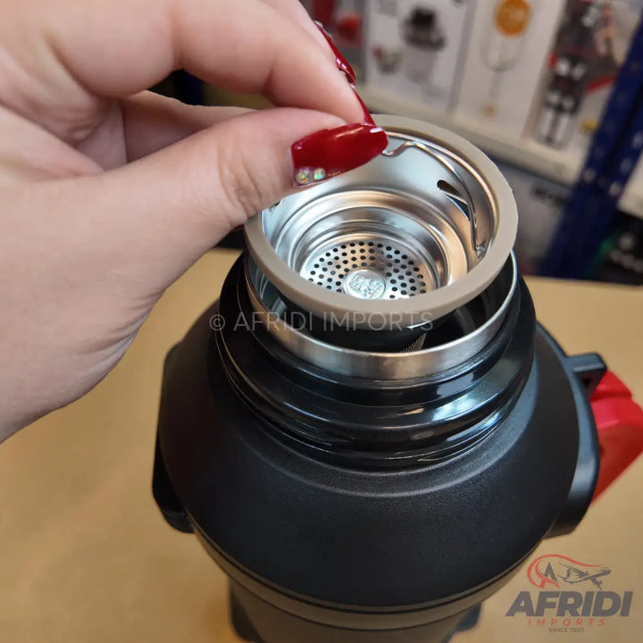 A person’s hand placing a metal sink strainer with a rubber gasket into what appears to be a garbage disposal unit.