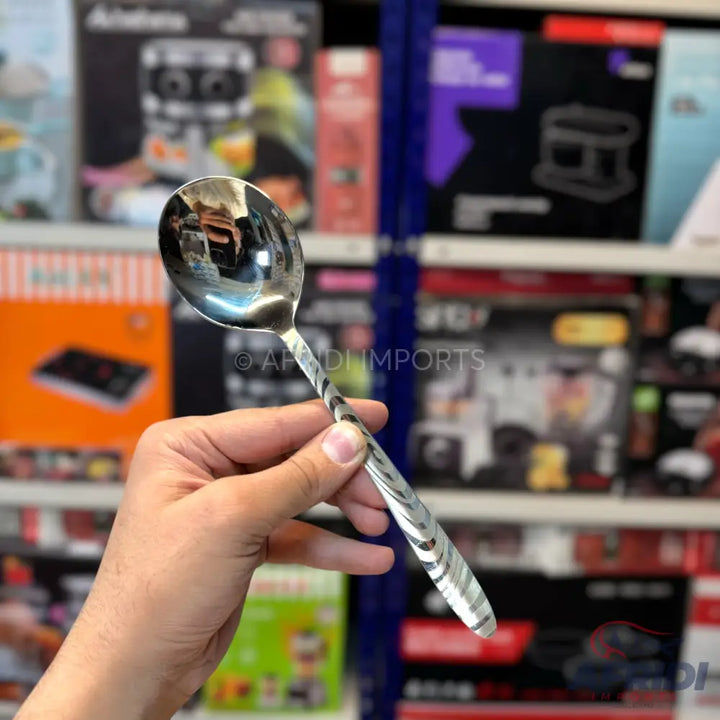 A stainless steel serving spoon with a patterned handle.
