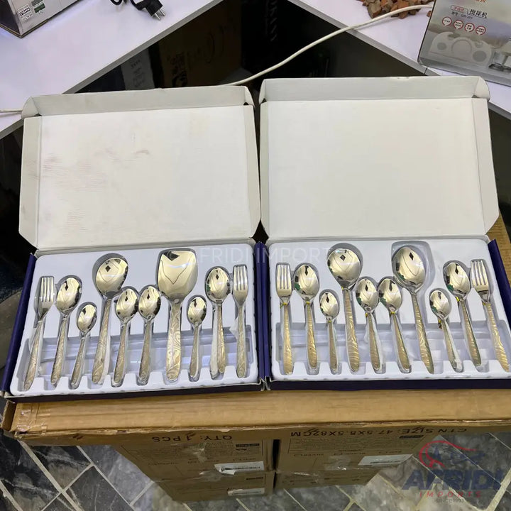 Two boxed sets of silver-colored flatware with decorative handles.