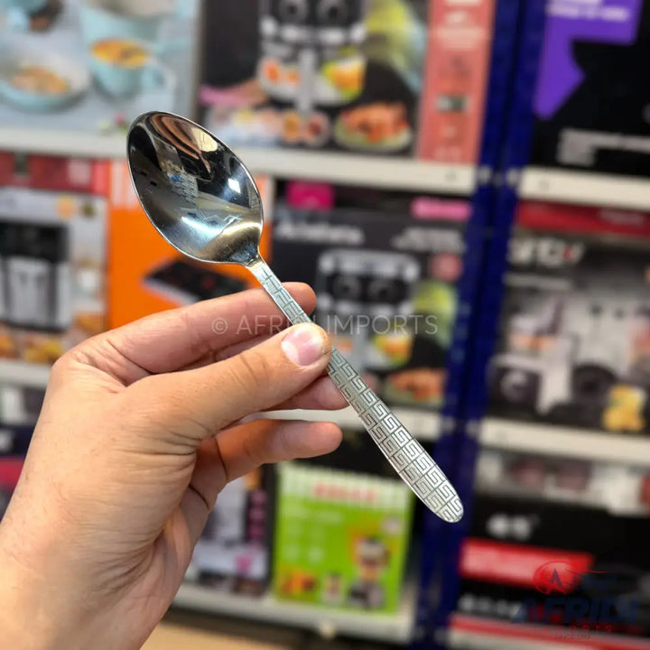 Shiny silver metal spoon with an etched geometric pattern on the handle.