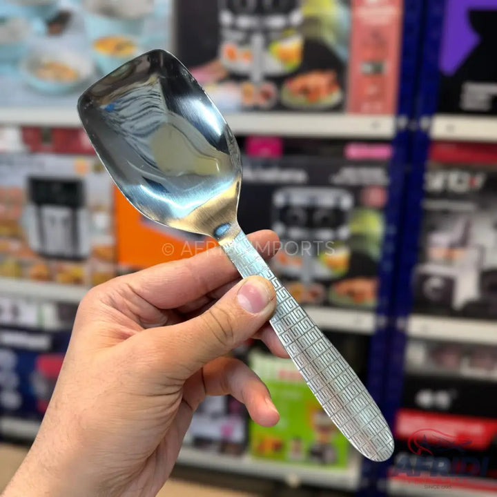 A shiny, stainless steel rice spoon with a textured handle.