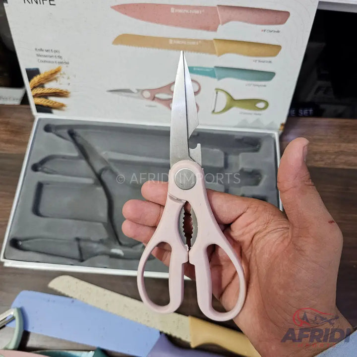 A pair of pink-handled kitchen shears with an integrated bottle opener and serrated grip.