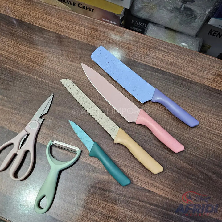 A set of pastel-colored kitchen knives, a peeler, and scissors.