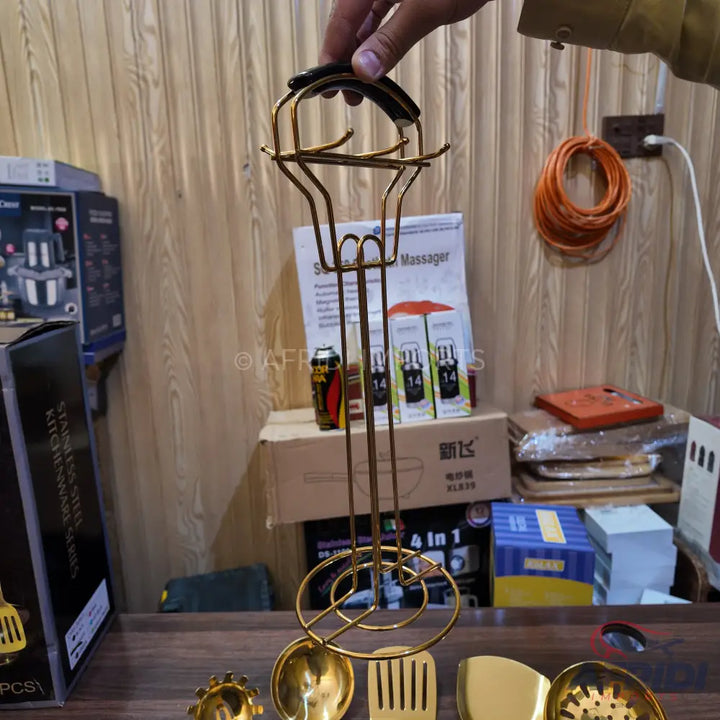 Gold-colored kitchen utensil holder with a handle and multiple hooks.