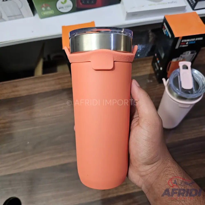 A peach-colored stainless steel tumbler with a clear lid and a silicone sleeve.