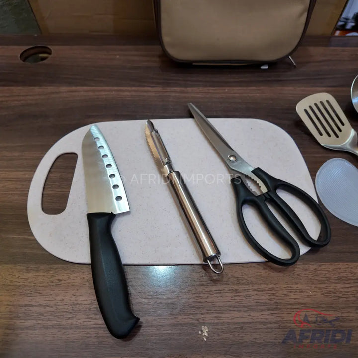 A set of kitchen tools including a knife, a peeler, and scissors on a cutting board.