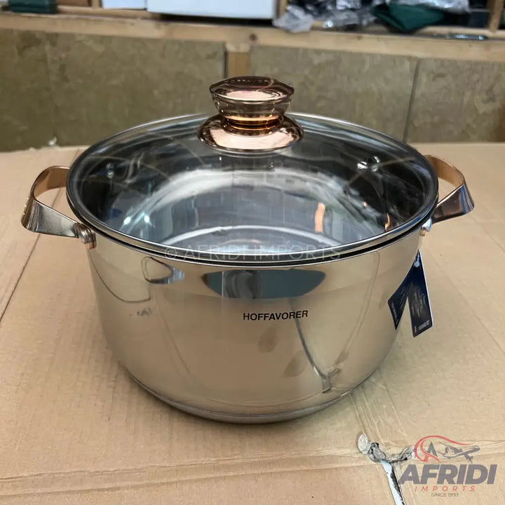 Stainless steel pot with a glass lid and copper-colored handles.