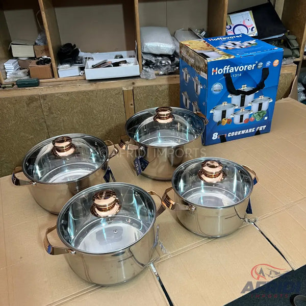A set of stainless steel pots with glass lids and rose gold handles.