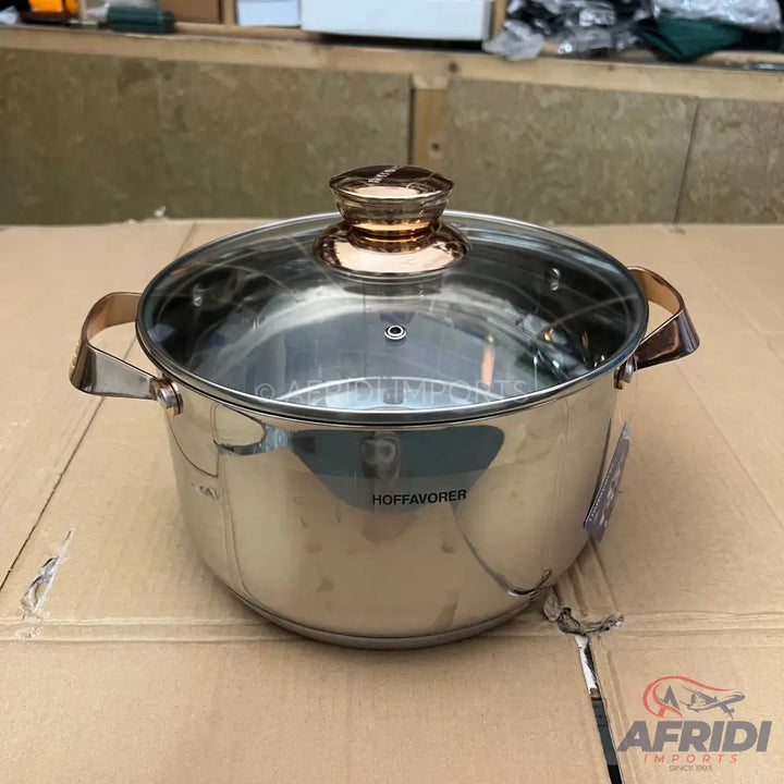 Stainless steel cooking pot with a glass lid and rose gold handles.