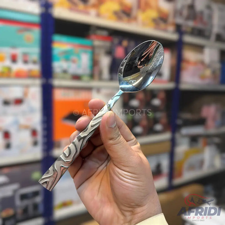 A metal serving spoon with a patterned handle.